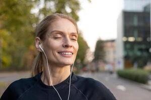 glimlachen vrouw met Gesloten ogen verloren in muziek- terwijl gebruik makend van wit oortelefoons, genieten van een zonnig dag in de stad. foto