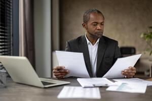 echt zelfverzekerd zakenman financier binnen kantoor Bij werkplaats controle documenten, rapporten en contracten. senior Mens in bedrijf pak werken Aan papierwerk, accountant met rekeningen. foto