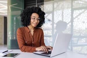 jong vrouw werknemer programmeur werken Bij werkplaats binnen kantoor met laptop, bedrijf vrouw typen Aan toetsenbord gelukkig lachend, tevreden met werk en prestatie resultaten. foto