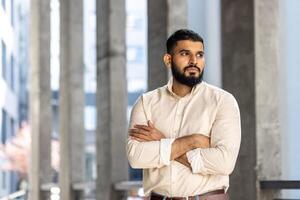 zelfverzekerd Mens staand met armen gekruiste in een modern stad milieu foto