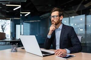 attent en echt jong Mens zakenman, freelancer, ontwerper, architect werken in de kantoor Bij een laptop met koptelefoon. foto