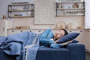 jong mooi Aziatisch vrouw resting en slapen Bij huis aan het liegen Aan sofa onder deken foto