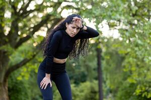 een fit vrouw in training uitrusting pauzeert voor rust uit temidden van groen, vastleggen de essence van Gezondheid en welzijn. foto