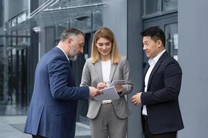 gelukkig en vrolijk verschillend bedrijf team van analisten ingenieurs programmeurs bespreken nieuw app Aan tablet, groep van bedrijf mensen hebben pret pratend tevreden met werk resultaat. foto