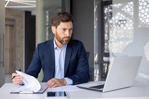 geconcentreerd mannetje accountant herzien documenten met een echt uitdrukking in een modern kantoor instelling, illustreren professionaliteit en focus. foto