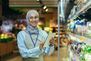 portret van gelukkig en glimlachen verkoper vrouw in hijaab, moslim vrouw met tablet glimlachen en op zoek Bij camera, verkoopster in de buurt veld- met groenten en salade producten kiest en zeven termijn foto