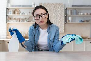 portret van ontevreden jong Aziatisch vrouw, huisvrouw in bril op zoek Bij camera foto