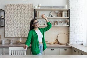 jong mooi vrouw in bril en groen overhemd in de keuken hebben pret foto