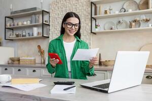 jong latina vrouw werk met financieel papieren Bij huis tellen Aan rekenmachine voordat betalen belastingen foto