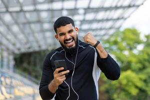 energiek Mens genieten van muziek- Aan zijn telefoon buitenshuis foto