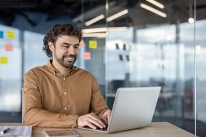 volwassen ervaren programmeur binnen kantoor Bij werkplek, zakenman volwassen Mens typen Aan laptop toetsenbord, bedrijf arbeider in overhemd tevreden met prestatie resultaten lachend. foto