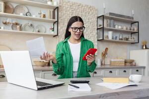 teleurgesteld vrouw Bij huis met papier werk, brunette in keuken tellen rekeningen. foto