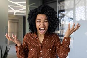 een jong professioneel vrouw verschijnt geërgerd en geërgerd terwijl op zoek direct Bij de camera gedurende een telefoongesprek. benadrukt werkplaats spanning en afgelegen communicatie uitdagingen. foto