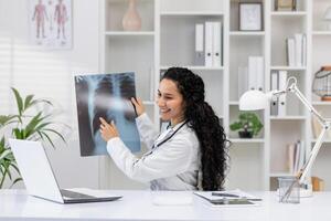 een vrolijk vrouw dokter onderzoekt een borst röntgenstraal in een goed uitgerust kliniek. zij is lachend, wijzend op positief resultaten en een comfortabel werken omgeving. foto