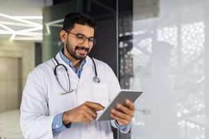 zelfverzekerd jong mannetje gezondheidszorg professioneel werken met een tablet in een helder medisch kantoor instelling, belichamen de mengsel van technologie en zorg. foto