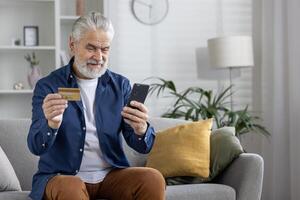 volwassen gebaard Mens comfortabel gebruik makend van zijn smartphone en credit kaart naar winkel online van huis. foto