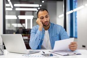 bezorgd Indisch Mens Bij huis of kantoor, op zoek over- papieren met laptop. concepten van werkdruk en deadline druk. foto