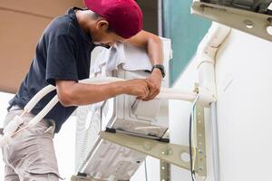 mannelijke technicus handen met behulp van een schroevendraaier voor het bevestigen van moderne airconditioner, reparatie en onderhoud, onderhoud en reparatie concept foto