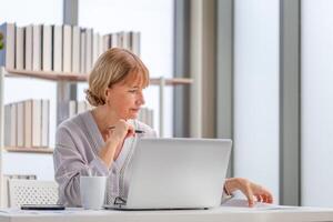 vrouw gebruik makend van laptop en smartphone Bij huis, volwassen vrouw controle hun rekeningen foto