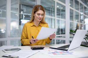 jong bedrijf vrouw, boekhouder, financieel analist is gefocust in de kantoor met documenten en rekeningen. foto