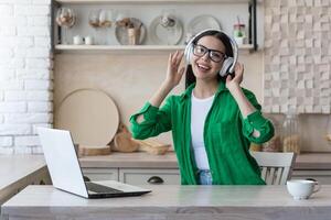 aantrekkelijk jong vrouw werken met laptop en luisteren muziek- Bij huis. foto