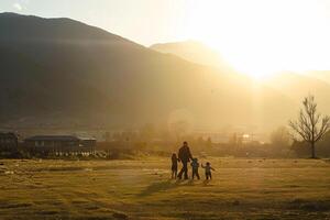 familie silhouet spelen in berg veld- Bij zonsondergang foto