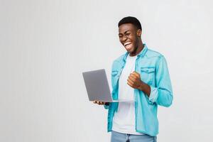 jong Mens staat vervelend een helder blauw overhemd houdt een laptop met een hand- foto