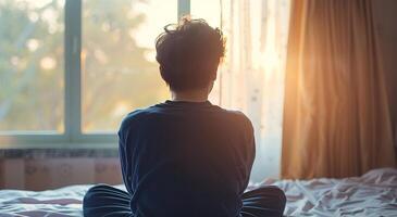 terug visie van jong Mens mediteren Aan de bed in de ochtend- foto