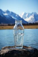 schoon drinken water in een fles tegen de achtergrond van een meer en bergen foto