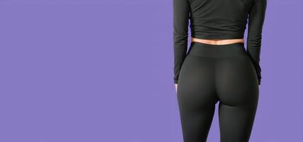 vrouw in zwart leggings Aan een Purper achtergrond terug visie, foto