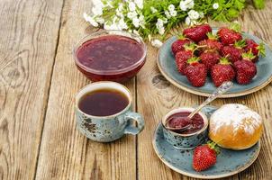 rijpe rode zoete aardbeienjam, verse bessen op houten tafel foto