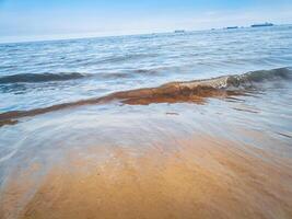 fotografie van golven Aan de strand met een Doorzichtig lucht voor een zomer achtergrond foto
