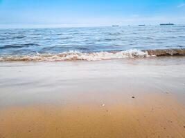 fotografie van golven Aan de strand met een Doorzichtig lucht voor een zomer achtergrond foto