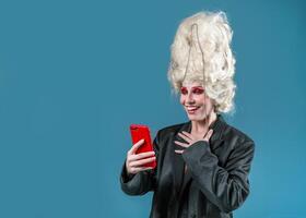 verrassing vrouw in Koninklijk pruik gebruik makend van smartphone in blauw studio foto