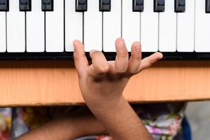 Aziatisch schattig meisje spelen de synthesizer of piano. schattig weinig kind aan het leren hoe naar Speel piano. kind handen Aan de toetsenbord binnen. foto