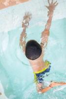 gelukkig Indisch jongen zwemmen in een zwembad, kind vervelend zwemmen kostuum langs met lucht buis gedurende heet zomer vakanties, kinderen jongen in groot zwemmen zwembad. foto
