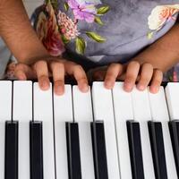Aziatisch schattig meisje spelen de synthesizer of piano. schattig weinig kind aan het leren hoe naar Speel piano. kind handen Aan de toetsenbord binnen. foto