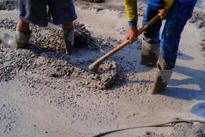 ndustrial fotografie. bouw werk activiteiten. arbeiders zijn schoffelen en menging cement met zand en stenen voor cement gietstukken. Bandung - Indonesië, Azië foto