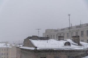 sneeuw dekens de daken van heilige petersburg, vastleggen een somber winter stadsgezicht temidden van een zwaar sneeuwval foto