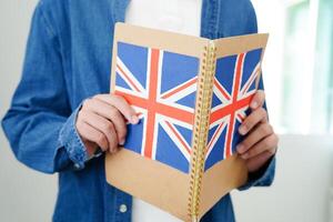 aan het leren engels, Aziatisch tiener- leerling Holding boek met vlag voor taal programma onderwijs. foto