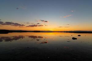 zonsondergang of zonsopkomst visie over- de meer met gedeeltelijk bewolkt lucht foto