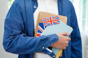 aan het leren engels, Aziatisch tiener- leerling Holding boek met vlag voor taal programma onderwijs. foto