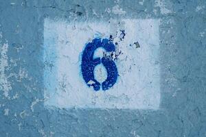 aantal zes geschilderd Aan een blauw gekrast muur in een rechthoek met pellen verf foto