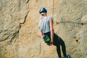 jong atletisch vrouw in uitrusting aan het doen rots beklimming buitenshuis. opleiding Oppervlakte voor buitenshuis activiteiten. extreem sport. foto