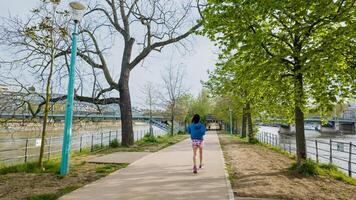 actief vrouw jogging langs een toneel- rivier- traject in lente, bevorderen Gezondheid en fitheid, geschikt voor Internationale vrouwen dag en nationaal rennen dag thema's foto