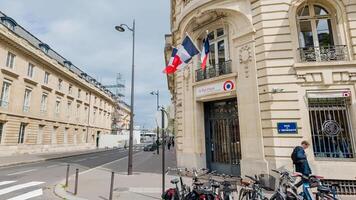 voorjaar dag in Parijs tonen de Frans vlag buiten een klassiek gebouw, met geparkeerd fietsen en een voorbijganger, gevangen genomen Aan april 14e, 2024 foto