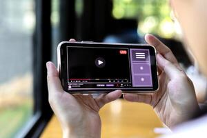 modern multimedia concept. inhoud creatie online streaming populair internetten, inkomsten genereren, sociaal media. vrouw horloges in online media toepassingen Aan smartphone foto