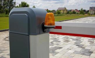 sluit de poort. automatisch beveiligingssysteem. automatisch invoersysteem. geel lichtsignaal met een straatbarrière. slagbomen automatisch beveiligingssysteem. foto