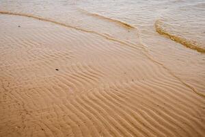 naadloos nat zand met zee water Aan een geheel achtergrond. leeg golvend zanderig zee onderkant. exotisch zanderig oceaan strand oppervlak. top visie. gemakkelijk, minimalistisch foto. ideaal concept voor banier, poster, advertenties. foto