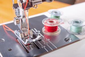 modern naaien machine perser voet met rood draad dichtbij omhoog foto